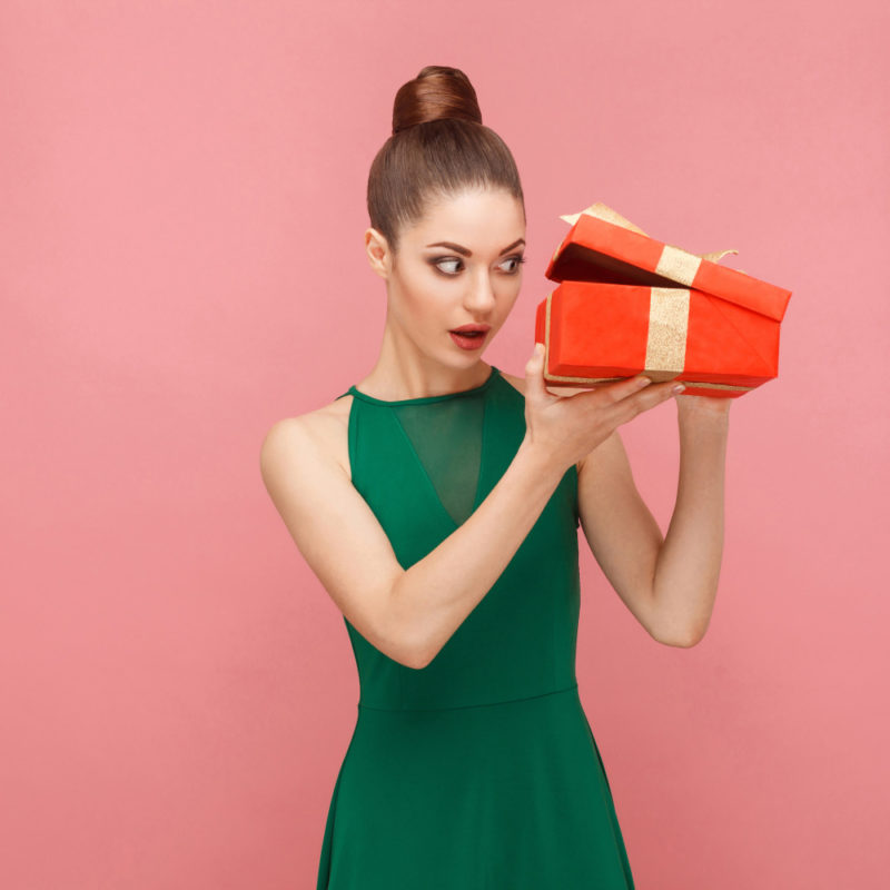 Woman unboxing red gift box looking inside.